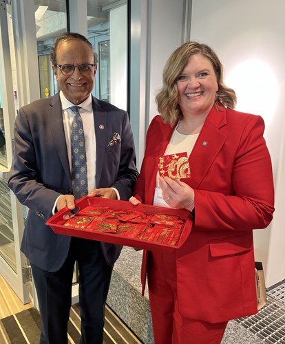 : Honourable Muhammad Yaseen, Minister of Immigration and Multiculturalism, and Kathryn Oviatt, Chief of the Commission and Tribunals, holding a red tray of Chinese red envelopes and handing them out during the Government of Alberta’s Lunar New Year celebration.